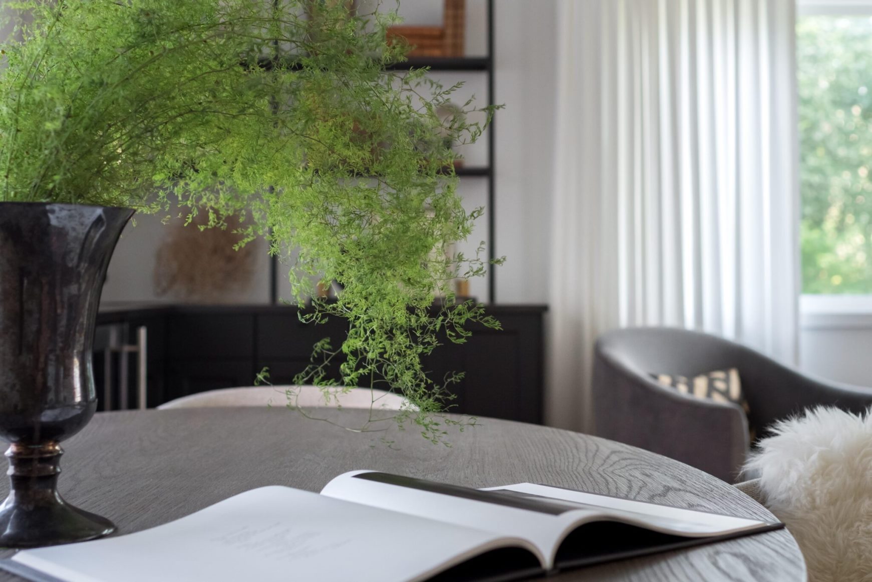 The focus on a wooden table with a book and a plant in a vase