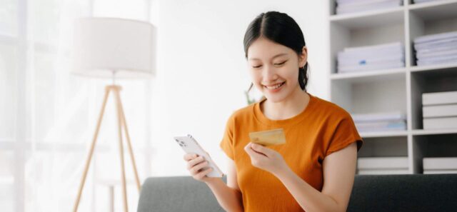 Young woman pays with a credit card for online shopping