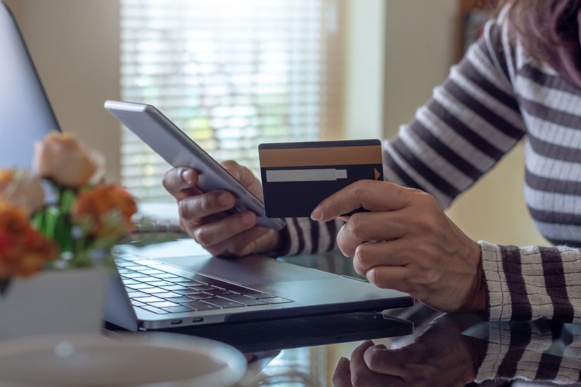 The woman holds a phone and a credit card in her hand