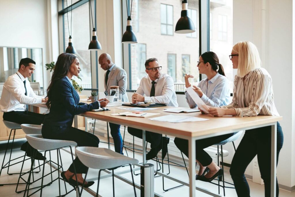 A group of people are sitting at a high table in the office